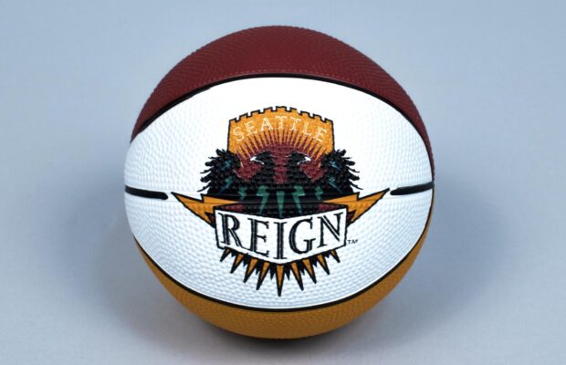 A basketball featuring the Seattle Reign logo from the American Basketball League (ABL). The logo shows two black birds in front of evergreen trees with the words 