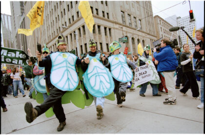 Three people dressed in homemade turtle costumes do the cancan in front of a building in downtown Seattle.