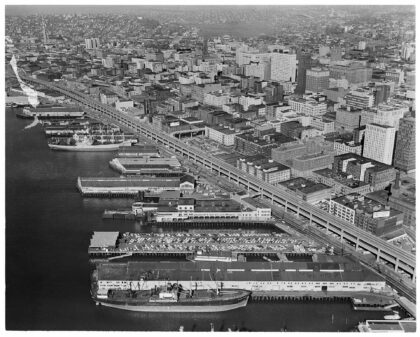 Aerial view of downtown Seattle waterfront in 1961 showing piers, cargo ships, and the Alaskan Way Viaduct.