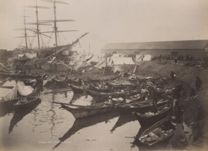 Black and white photograph of Native American canoes lined up along the beach of the Seattle waterfront.