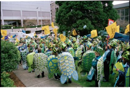 Large crowd of activists dressed as turtles protesting against the World Trade Organization (WTO), holding yellow flags and signs that say 'No to WTO' during the 1999 Seattle WTO protests.