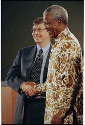 Nelson Mandela shaking hands with Bill Gates during a global health forum at the University of Washington, both smiling.