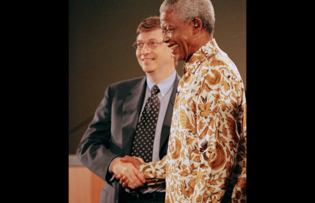 Nelson Mandela shaking hands with Bill Gates during a global health forum at the University of Washington, both smiling.