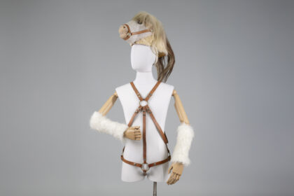 Mannequin wearing a leather harness costume with faux fur arm cuffs and a horse head mask.