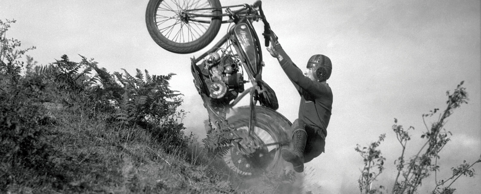 A person riding a motorcycle up a steep hill with only the rear wheel on the ground.