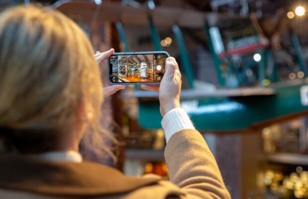 Color photograph of a person using a phone to photograph the Boeing B-1 airplane at MOHAI.