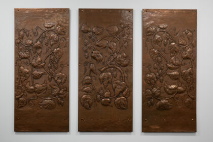 Three large copper panels with designs of hops hammered into them.