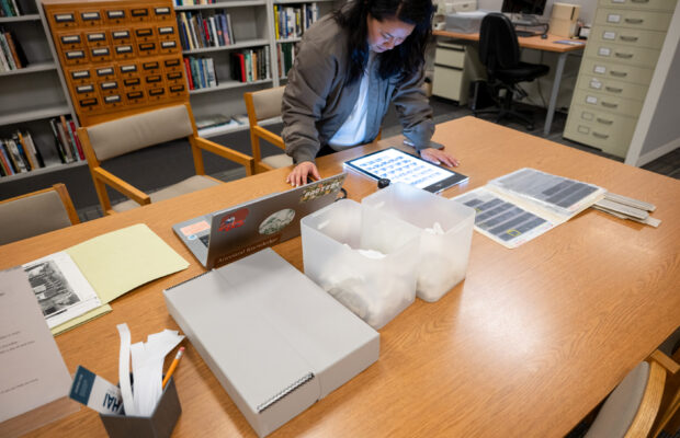 Photograph of curator's fellow Than Tan researching photos in the MOHAI collection.