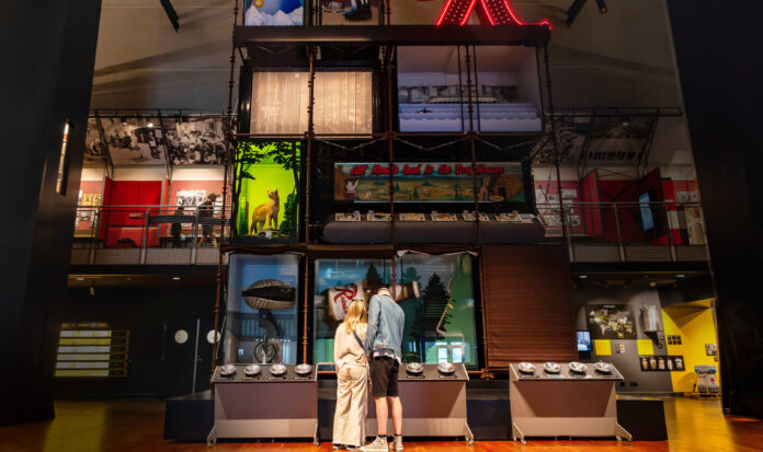A couple stands in the Grand Atrium at MOHAI engaging with an exhibit.