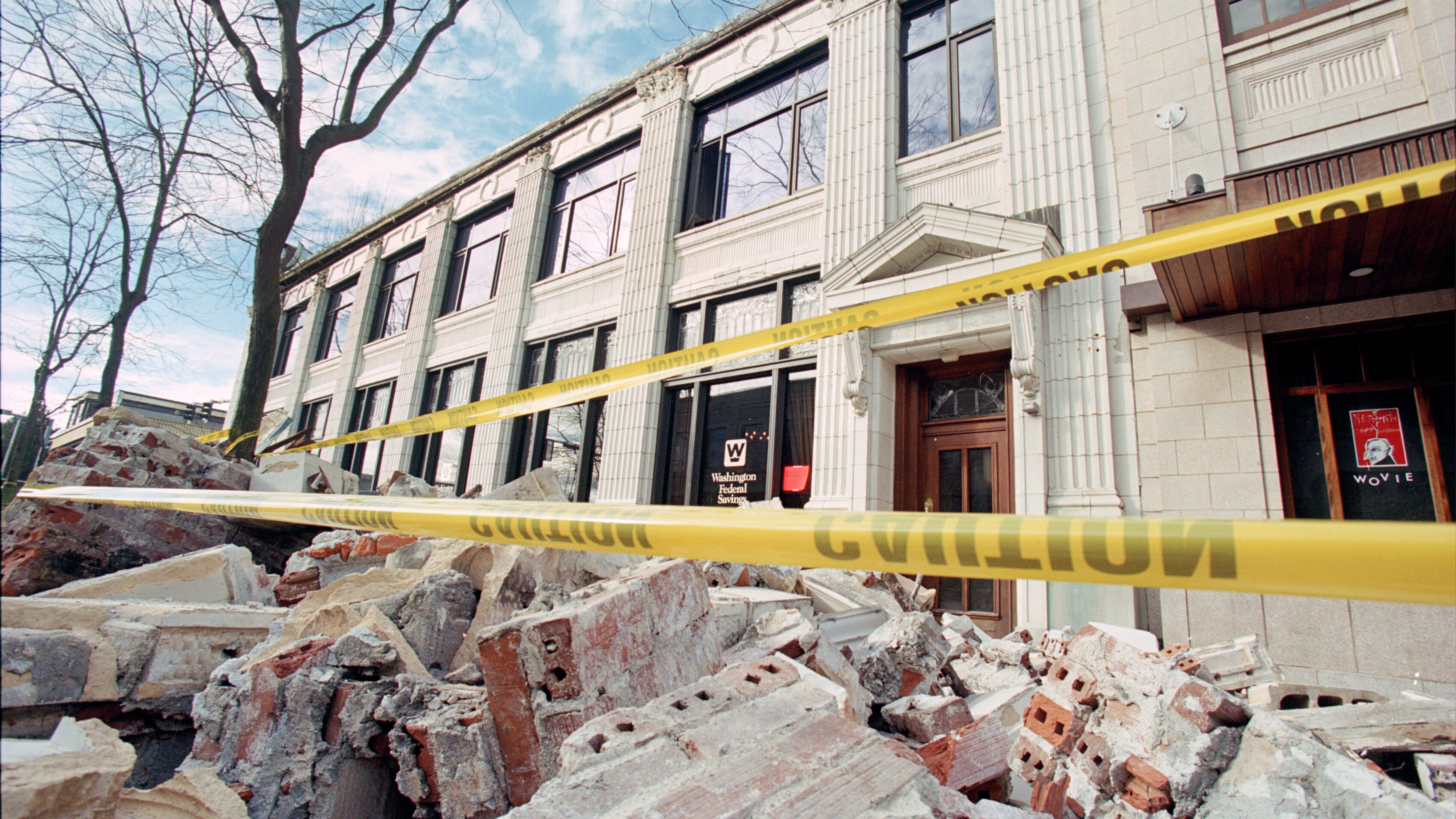 Exterior of the Washington Federal Savings building in Seattle, WA. Brick rubble and yellow caution tape is seen in the foreground.