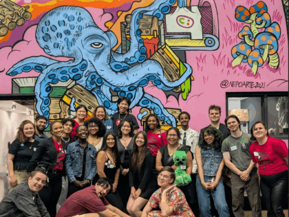 Members of The Washington Bus pose before a mural showing a blue octopus.