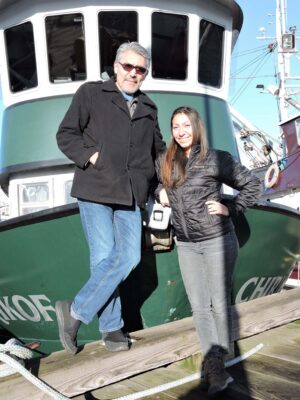 Photograph of Allison and Guy Demmert in front of a tugboat on a dock.