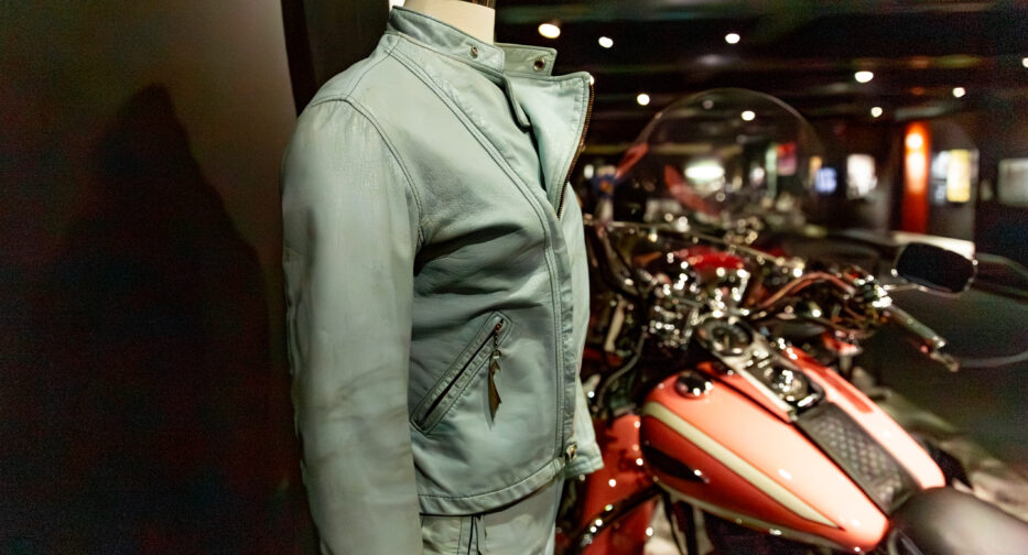A motorcycle riding outfit adjacent to a motorcycle on display at the MOHAI Kickstands Up! exhibit in downtown Seattle, WA.