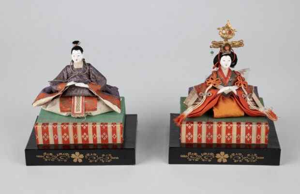 Emperor and Empress dolls from a Japanese Girls' Day set, dressed in ornate purple and red court garments and displayed on tiered platforms; part of MOHAI's Japanese American doll collection.