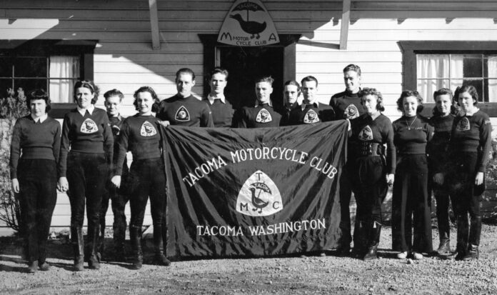Fourteen male and female members of the Tacoma Motorcycle Club with a team banner in 1937.