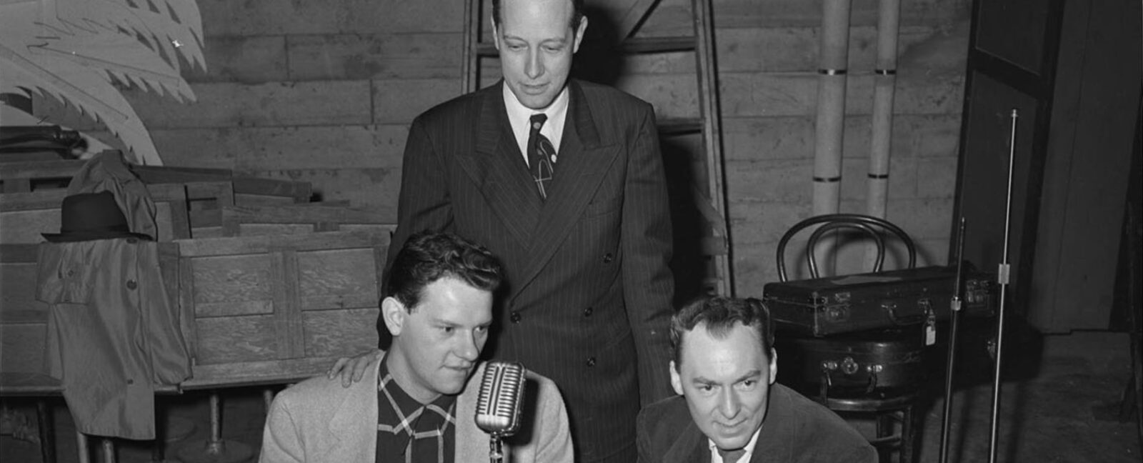 Woody Herman, right, and two unidentified men sit near a microphone for an interview with KRSC radio, backstage at the Civic Auditorium at 321 Mercer Street.